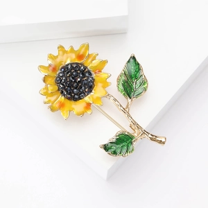 Détail d'une broche tournesol en émail avec pétales jaunes et feuilles vertes sur socle