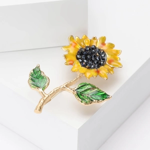 Broche tournesol en émail avec pétales jaunes et strass noirs sur fond blanc épuré