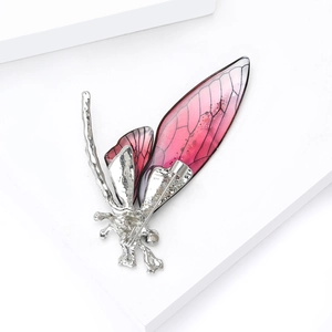 Dettaglio spilla a libellula con ali sfumate rosse e texture in argento fuso