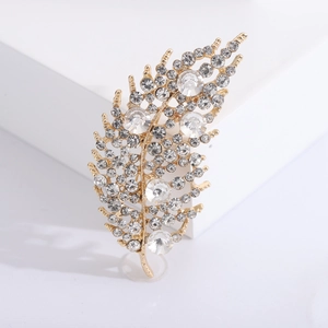Eleganter goldener Blatt-Brosche mit funkelnden Strasssteinen auf weißem Sockel