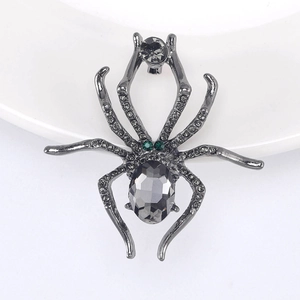 Macro shot of spider brooch with grey crystal body and emerald green rhinestone eyes