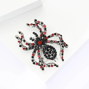 Macro shot of spider brooch with red and black rhinestones on a white geometric stand