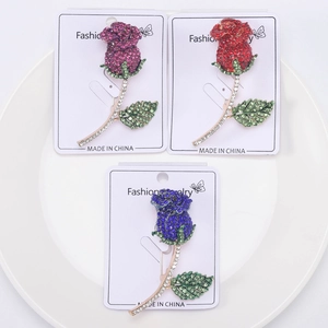 Dettaglio di spille a forma di rosa scintillanti in viola, rosso e blu con cristalli
