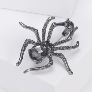 Macro shot of spider brooch with grey gemstone body and emerald green rhinestone eyes