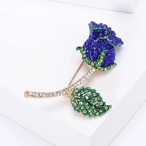 Elegante spilla a rosa dorata con strass blu profondi e accenti in cristallo verde