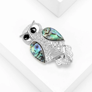 Retro owl brooch with natural abalone shell wings and black gemstone eyes on white stand