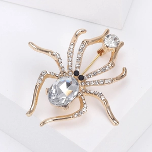 Detailed view of a gold spider brooch with white rhinestones and a large crystal center