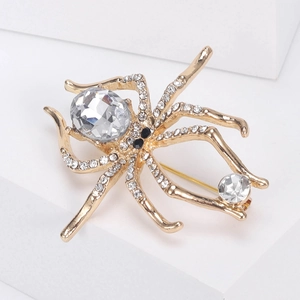 Detail of a gold spider brooch with crystal rhinestones and a large oval gemstone center