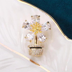 Detalle macro del broche de maceta de cristal dorado con pétalos de circón blanco