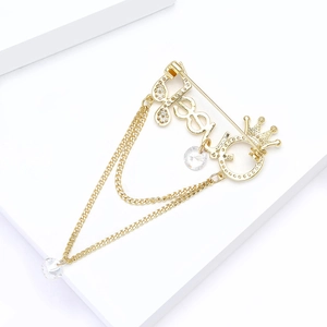 Macro shot of gold brooch with crown, '88' motif, double tassels and clear crystal pendants