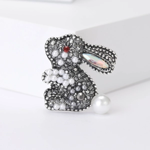 Close-up of cute rabbit brooch with grey rhinestones and white pearl details