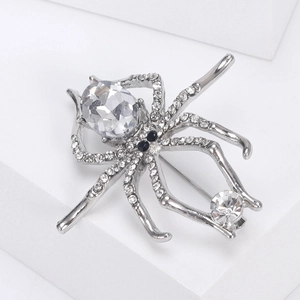 Macro shot of silver spider brooch with clear crystal rhinestones on white block
