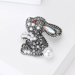 Macro view of crystal rabbit brooch featuring vintage alloy frame and large pearl tail