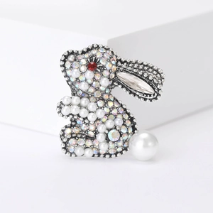 Detailed view of rabbit brooch featuring iridescent rhinestones and white pearls on silver