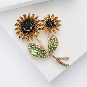 Detail of sunflower brooch with sparkling orange and green rhinestones on gold base