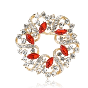 Eleganter Gold-Kranz-Brosche mit roten Markasit-Steinen und weißen Kristallen auf Weiß
