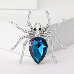 Close-up of alloy spider brooch with dark blue teardrop gem and white rhinestones