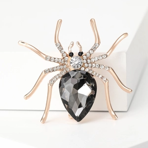Close-up of spider brooch with grey teardrop gemstone and rose gold rhinestone details