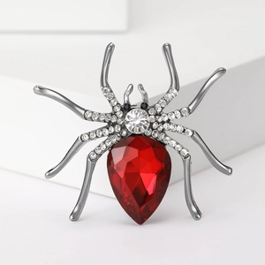 Macro view of a spider brooch featuring a large red pear-shaped gem and white rhinestones