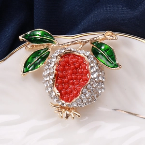 Vue détaillée de la broche grenade en strass avec perles rouges et feuilles en émail