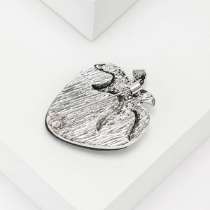 Vintage silver strawberry brooch with textured metal finish on a white geometric stand