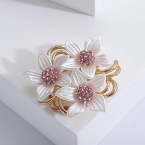 Élégante broche camélia blanc avec zircons roses sur une branche en alliage doré