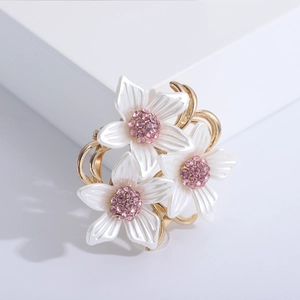 Broche florale aux pétales nacrés et cristaux roses sur une base dorée