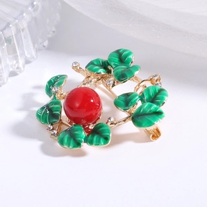Detail of floral wreath brooch with green enamel leaves and red center bead accent