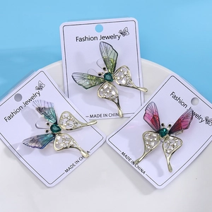 Three hollow butterfly brooches in green, blue, and red colors with rhinestone details