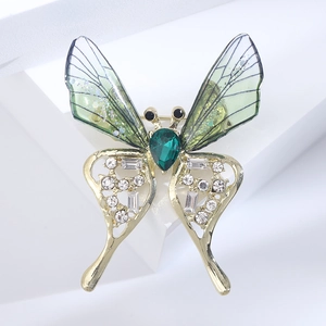 Close-up of butterfly brooch featuring translucent green wings and gold metal details