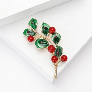 Creative enamel leaf brooch with red pearls on a minimalist white platform stand