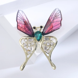 Close-up of butterfly brooch with gradient purple wings and emerald green gemstone core