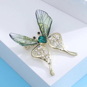 Macro detail of butterfly brooch with green gems and rhinestones on a geometric stand
