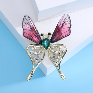 Elegant butterfly brooch with purple gradient wings and green gemstone on a blue background