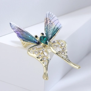 Macro shot of butterfly brooch with gradient wings, emerald stone and gold metalwork
