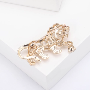 Detailed view of the hollow gold lion brooch with intricate carving on white display