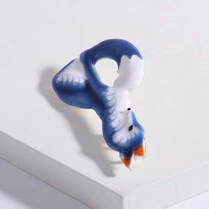 Detail view of a cute blue and white enamel fox brooch on a textured display block