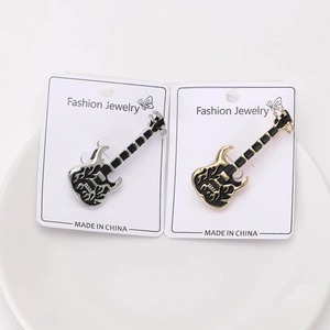 Close-up of guitar enamel pins with flame relief on backcard in a white dish