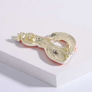 Detailed back view of a golden fox brooch featuring safety pin closure on white stone