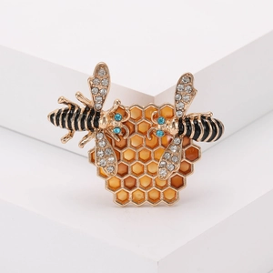 Broche de abeja dorada y panal con esmalte ámbar y cristales sobre fondo blanco puro