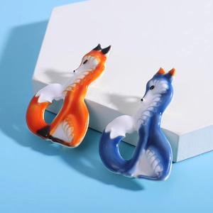 Detail of cute enamel fox brooches in orange and dark blue on white geometric display