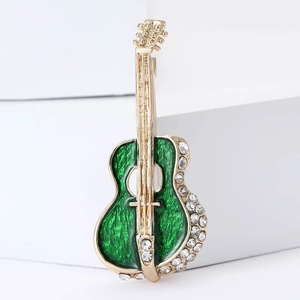 Elegant gold cello brooch with green enamel and crystal accents on a white stand
