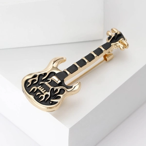 Detailed macro shot of a black enamel guitar brooch with artistic hollow flame patterns
