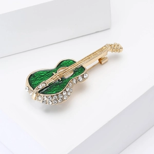 Close-up of a golden cello brooch with green enamel and sparkling white zircon inlays