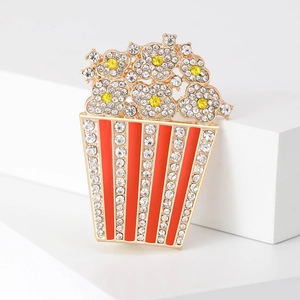 Dettaglio spilla a popcorn in lega con smalto rosso e strass bianchi brillanti