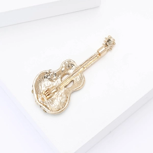 Detail view of the golden cello brooch back showing a secure metal safety pin clasp