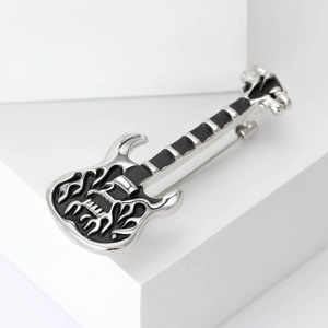 Detailed macro view of an electric guitar brooch with black enamel and flame patterns