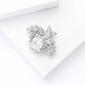 Silver bee brooch back view showing the safety pin clasp on a white platform