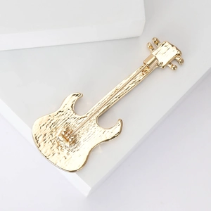 Golden alloy electric guitar brooch with artistic texture on a white geometric background