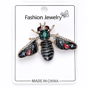 Close-up of a gold bee brooch with a green crystal back and colorful rhinestones